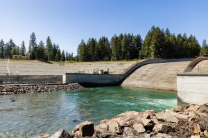 A photograph of Cle Elum Dam. Turquoise water sits below the dam on a sunny day.